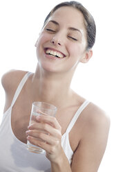 Young woman holding glass of water, eyes closed, smiling, close-up - WESTF03210