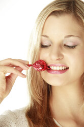 Junge Frau hält verpackte Süßigkeiten zwischen den Zähnen, Nahaufnahme - LDF00445