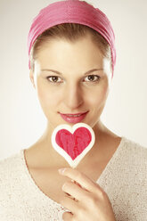 Young woman holding heart shaped lollipop, close-up, portrait - LDF00443