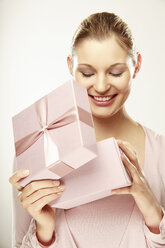 Junge Frau beim Öffnen eines Geschenkkartons, lächelnd, Nahaufnahme - LDF00422