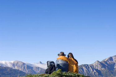 Couple sitting in mountains, looking at view, rear view - HHF01110