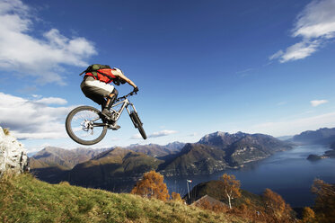 Italy, Lake Como, man performing jump on bicycle - FFF00721