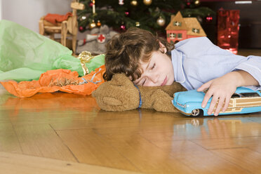 Schlafender Junge unter dem Weihnachtsbaum, Spielzeugauto in der Hand - WESTF04100