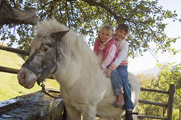 Zwei Mädchen reiten auf einem Pony - HHF01228