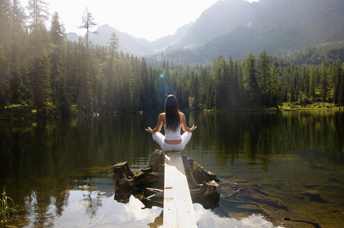 Woman exercising yoga at lake, rear view - HHF01146