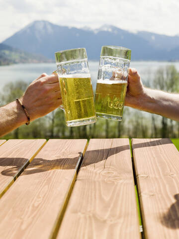 Deutschland, Bayern, Tegernsee, zwei Männer stoßen mit Biergläsern an, Nahaufnahme, lizenzfreies Stockfoto