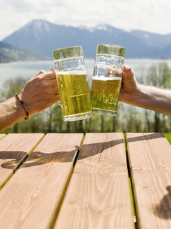 Germany, Bavarian, Tegernsee, two men toasting with beer glasses, close-up - KMF00685