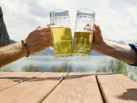 Deutschland, Bayern, Tegernsee, Männer stoßen mit Biergläsern an - KMF00684