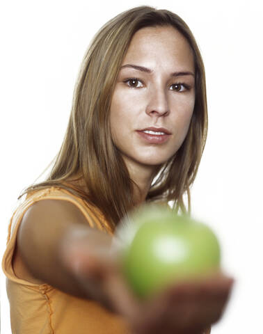 Junge Frau mit grünem Apfel in der Hand, mit Mütze, lizenzfreies Stockfoto