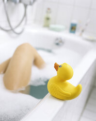 Frau badet in der Wanne mit gelber Gummiente im Vordergrund - THF00434