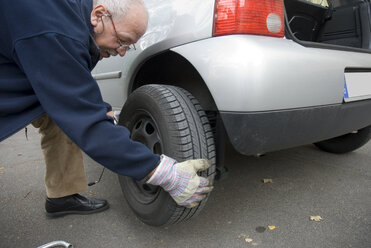 Senior man changing car tyre, close-up - NHF00295