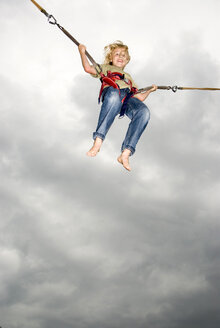 Boy (10-11) on bungee swing, smiling, low angle view - NHF00286