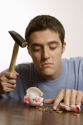 Young man with hammer and broken piggy bank - LDF00473