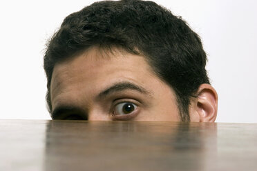 Young man hiding behind table, portrait - LDF00463