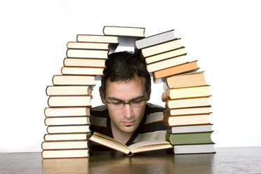 Junger Mann liest neben gestapelten Büchern, Nahaufnahme - CLF00300