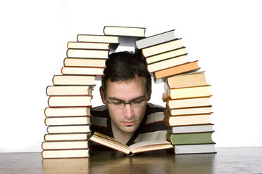 Young man reading by piled books, close-up - CLF00300