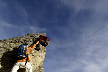 Junges Paar klettert auf Berggipfel, Mann hilft Frau, Rückansicht - WESTF04260