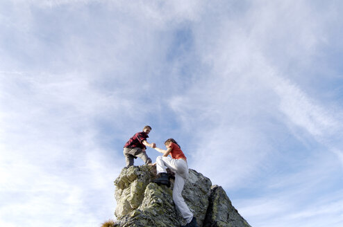 Junges Paar beim Klettern auf einem Berggipfel, Mann hilft der Frau, Tiefblick - WESTF04218
