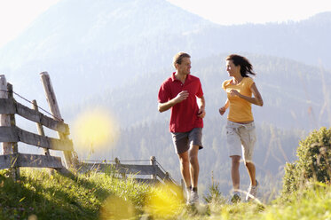 Junges Paar joggt am Holzzaun, Berge im Hintergrund - WESTF04202