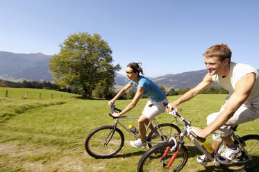 Junges Paar fährt Mountainbike, lächelnd, Seitenansicht - WESTF04184