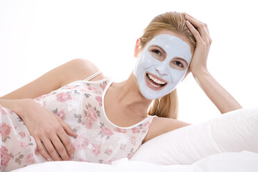 Frau mit Schönheitsmaske im Gesicht auf dem Bett liegend - MAEF00251
