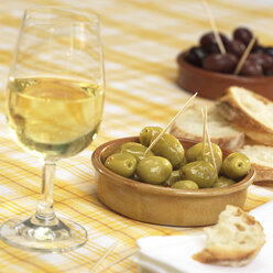 Ein Glas Wein mit Oliven und Weißbrot auf dem Tisch - WESTF04619