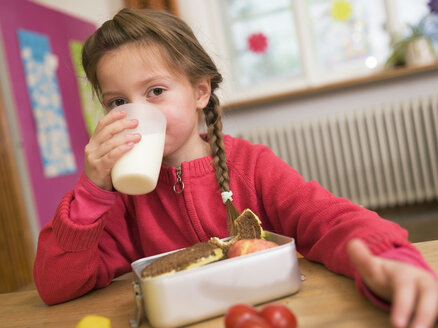 Mädchen (4-7) am Schreibtisch sitzend, trinkt ein Glas Milch, Porträt - WESTF04549