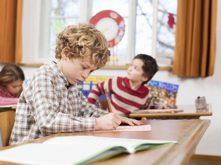 Children (4-7) writing exam in classroom, focus on boy - WESTF04515