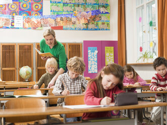 Kinder (4-7) schreiben eine Prüfung im Klassenzimmer - WESTF04514