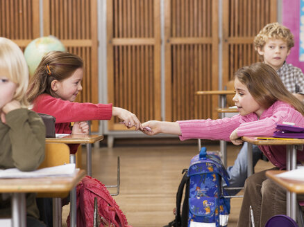 Girls (4-7) exchanging notes in classroom - WESTF04504