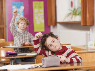 Kinder (4-7) im Klassenzimmer, Fokus auf Junge mit Hand im Haar im Vordergrund - WESTF04502