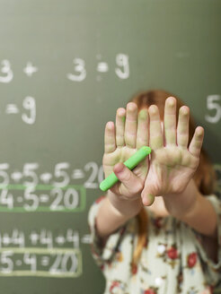 Girl (6-7) standing by blackboard and covering face with hands, close-up - WESTF04487