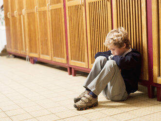 Boy (4-7) sitting in front of locker, side view - WESTF04450