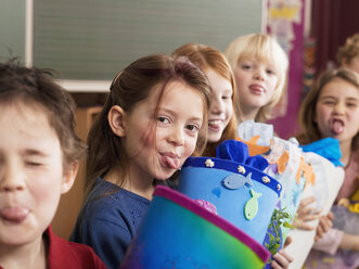 Children (4-7) holding school cone, sticking out tongue - WESTF04442