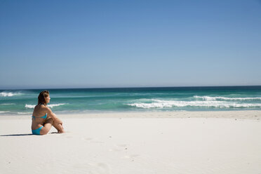 Junge Frau sitzt am Strand - WESTF04992