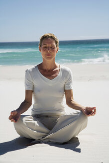 Woman exercising yoga on beach - WESTF04989