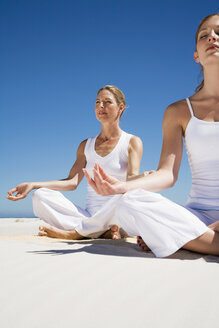 Two women exercising yoga on beach - WESTF04961
