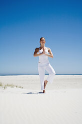 Woman exercising yoga on beach - WESTF04945