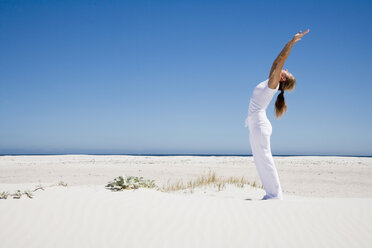Woman exercising yoga on beach - WESTF04941