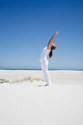 Woman exercising yoga on beach - WESTF04940