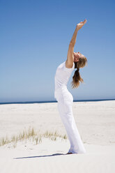 Woman exercising yoga on beach, side view - WESTF04939