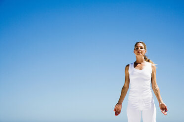 Woman exercising yoga on beach, low angle view - WESTF04928