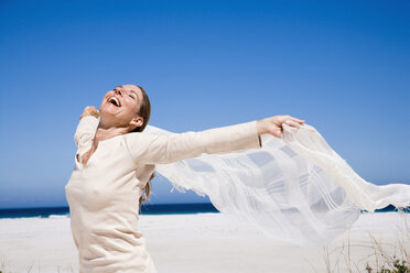 Woman on beach, holding shawl - WESTF04896