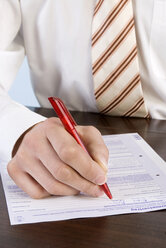 Businessman filling in application form, close-up, mid section - WESTF04796