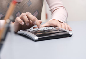 Woman using calculator, mid-section - WESTF04772