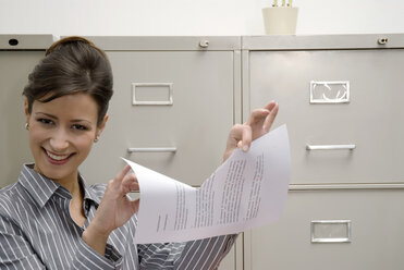 Woman tearing document, smiling, portrait - WESTF04760