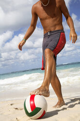 Young man playing football on beach - PKF00023