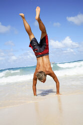 Junger Mann macht Handstand am Strand - PKF00007