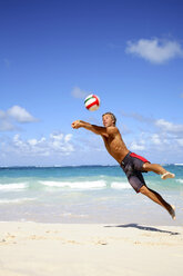 Junger Mann spielt Volleyball am Strand - PKF00002