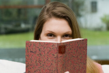 Young woman with book a twinkle in her eye - NHF00467